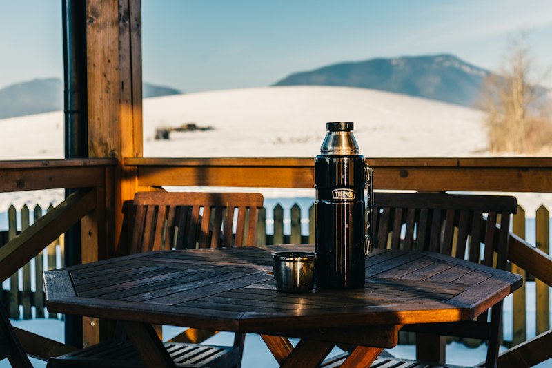 Porch table with a coffee flask overlooking snowy mountains