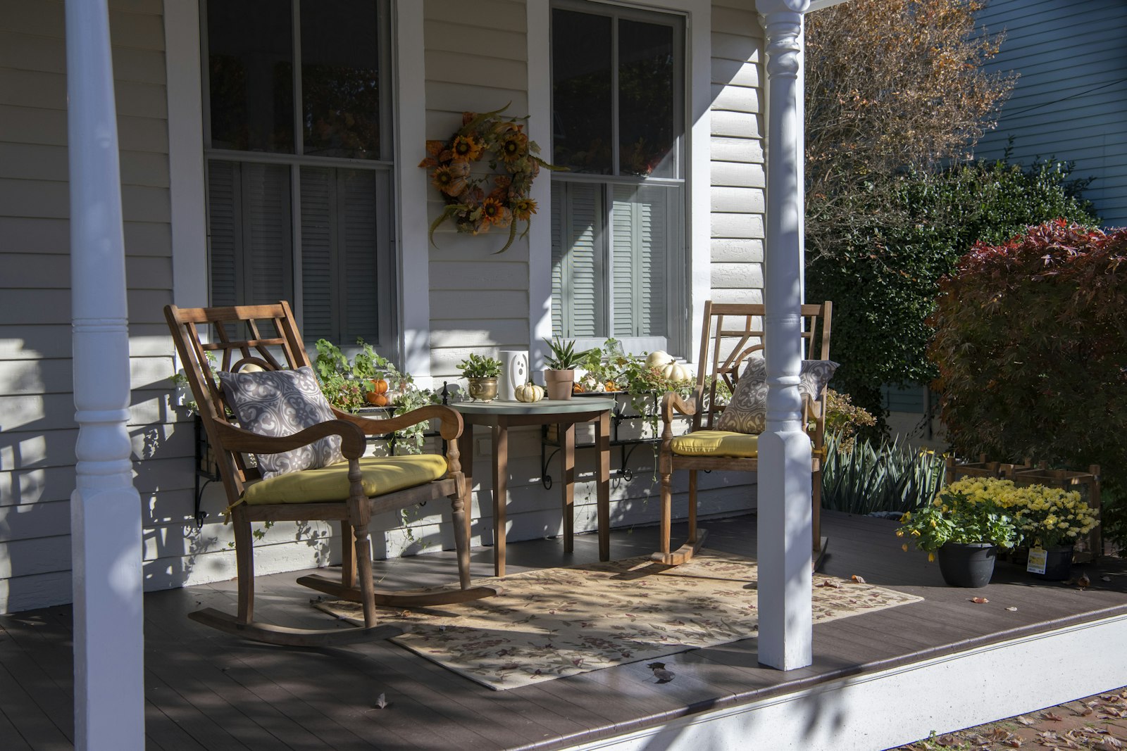 Welcoming front porch with wooden chairs, a table and potted plants