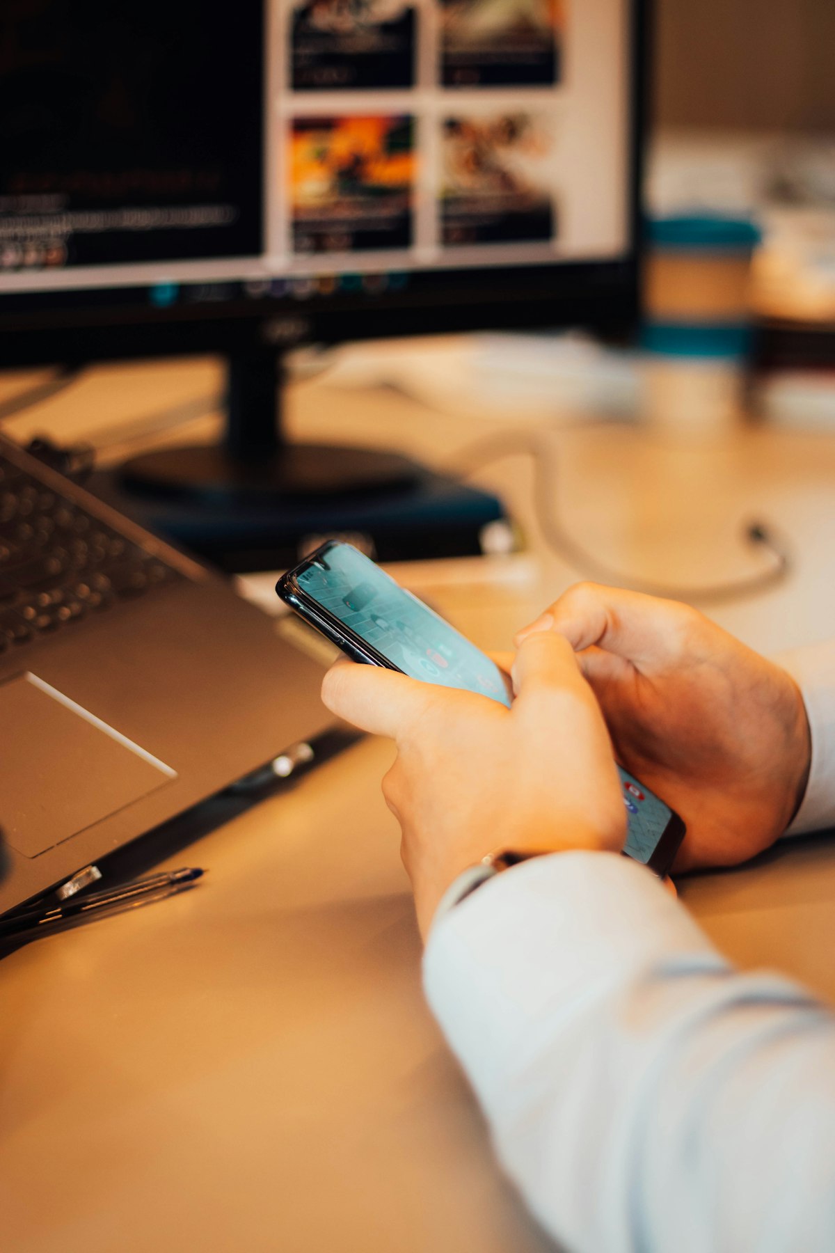 Person answering messages on a phone at a desk beside a laptop